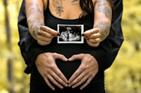 a pregnant woman with tattoos holding a photo of a baby