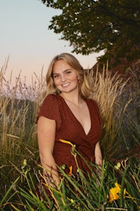 a woman in a red dress standing in a field of tall grass