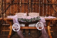 a table decorated with tulle and lights in a barn