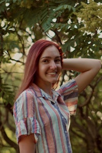 a woman in a striped shirt standing next to a tree