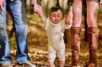 a family holding hands while walking through the woods