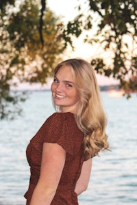 a woman in a brown dress standing next to a body of water