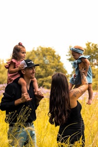 a family in a field holding a baby in their arms