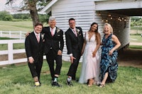 a group of bridesmaids and groomsmen pose for a photo in front of a barn