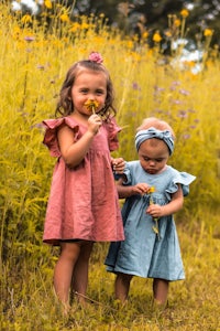 two little girls standing in a field with flowers