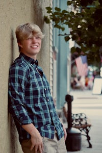 a young man leaning against a wall