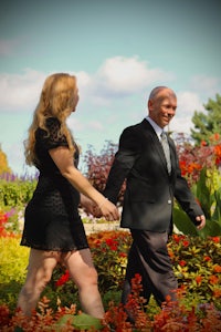 a man and a woman walking through a field of flowers