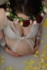 a pregnant woman in a bath with flowers on her belly