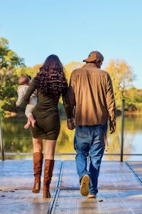 a man and woman holding a baby on a dock